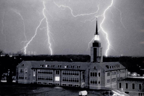 Black and white photo landscape photo of Kearney Hall surrounded by lightning bolts.