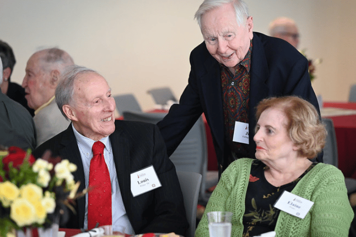 Three alumni chatting at a luncheon