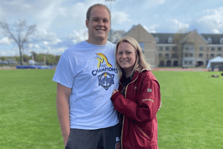 A young adult couple standing together with Founders Hall in the background