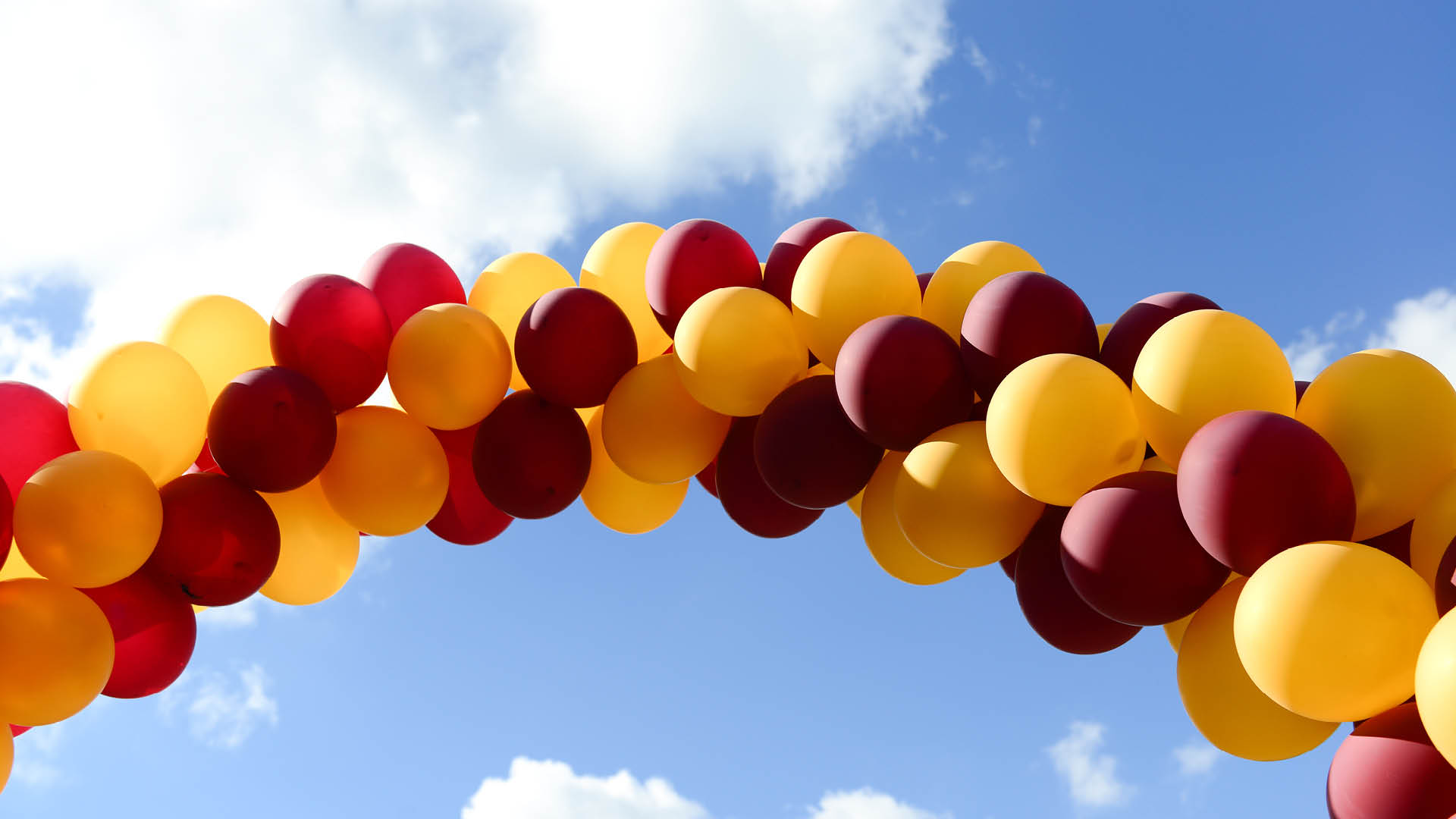 Red and gold balloons against a blue sky