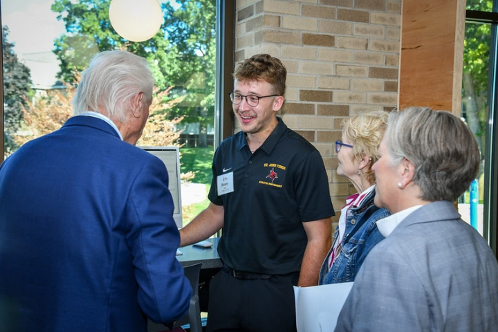 A student discusses his research with alumni