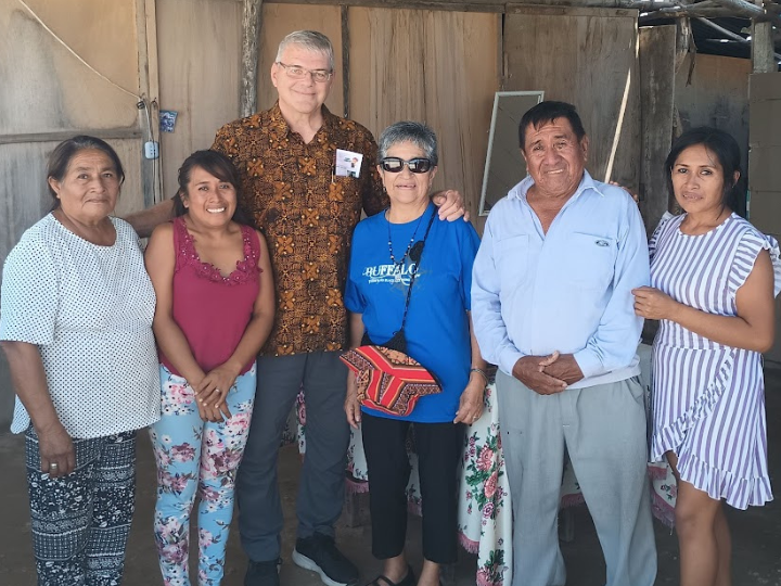 A group of six individuals posing for a photo inside a home in Peru