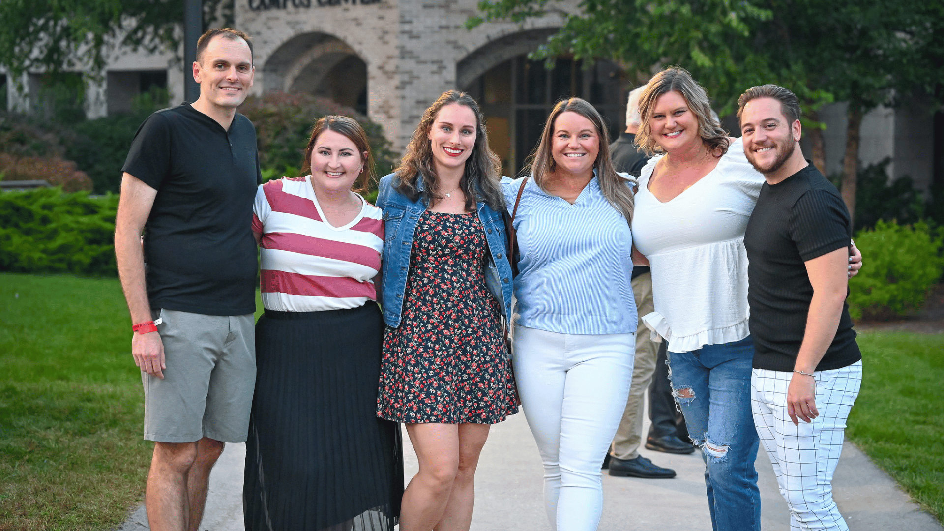 A group of six alumni together on campus