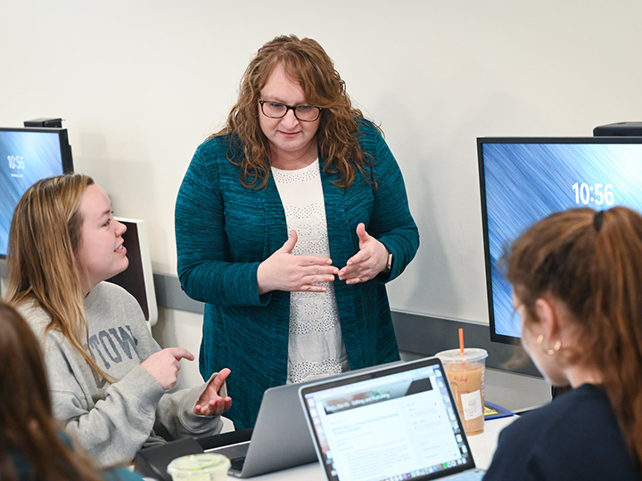 A professor talking with a student over a laptop.