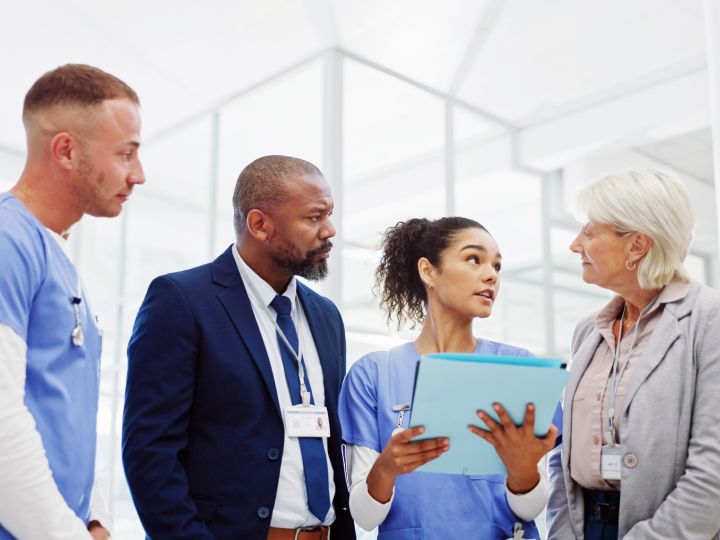 A group of people with name badges talking in a hospital.