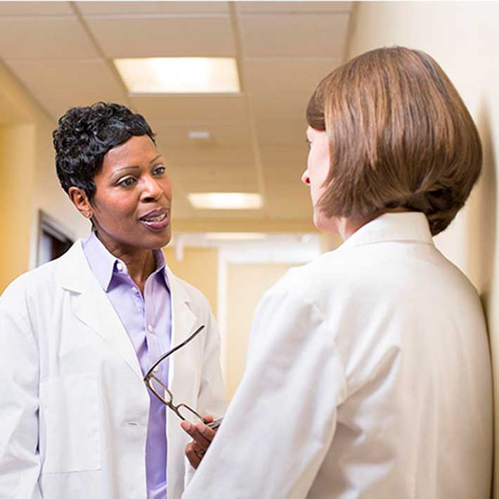 Two nurses talking in a hallway. 