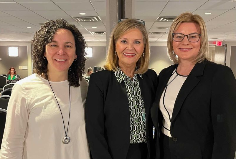 Three smiling women at a conference.