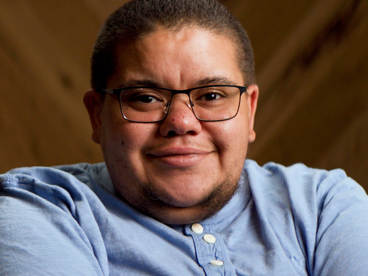 A smiling man in a blue polo shirt, wearing glasses.