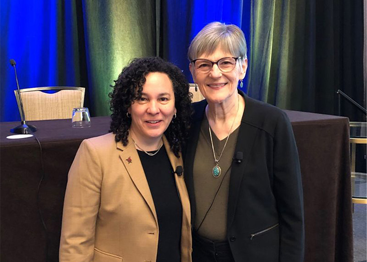 Two smiling women at a conference.