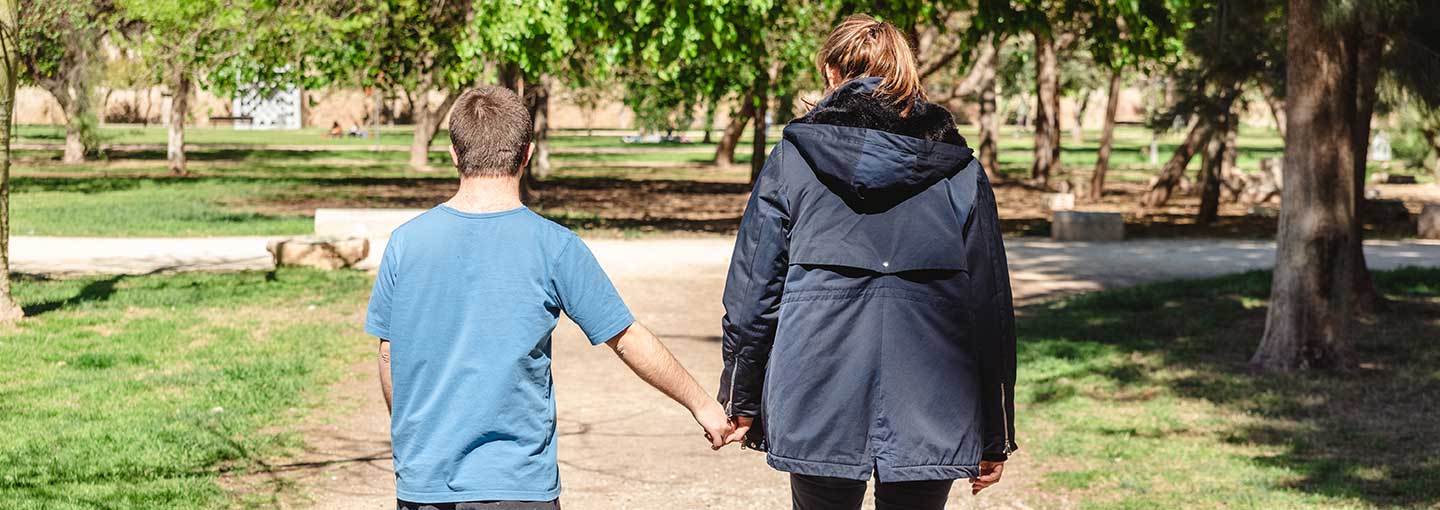 Person with Down syndrome accompanied by an assistant to help him.