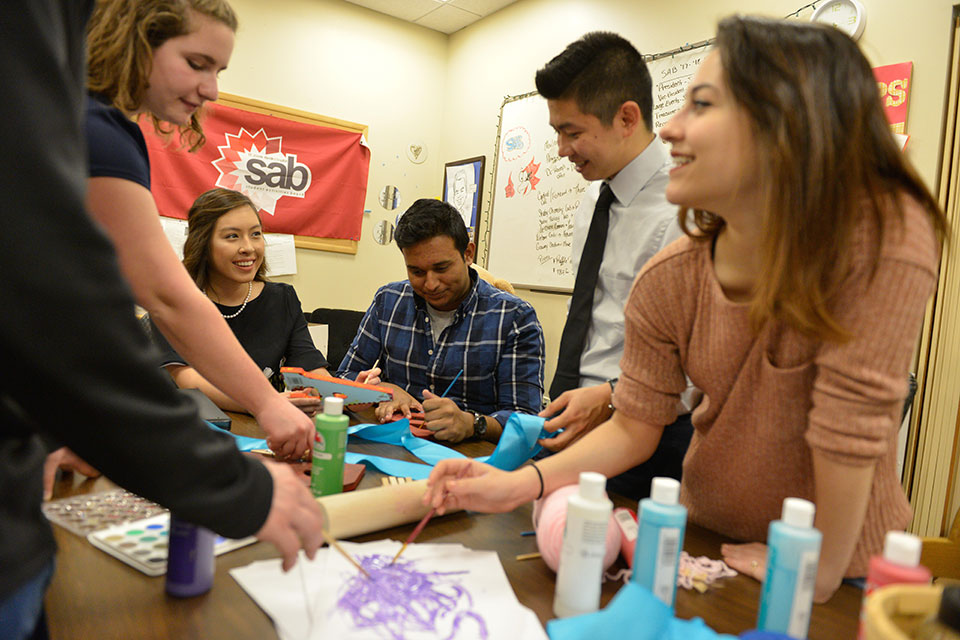 Students create posters during a club meeting.