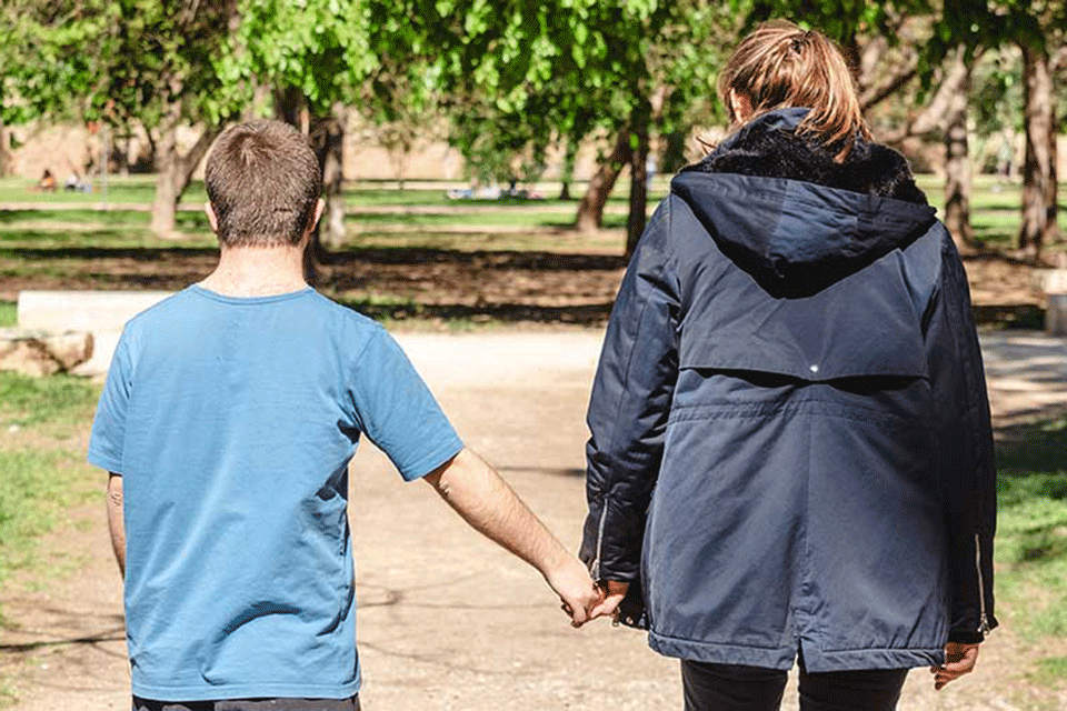 Person with Down syndrome accompanied by an assistant to help him.