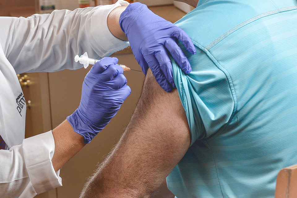 A community pharmacist administers a flu shot to a patient.