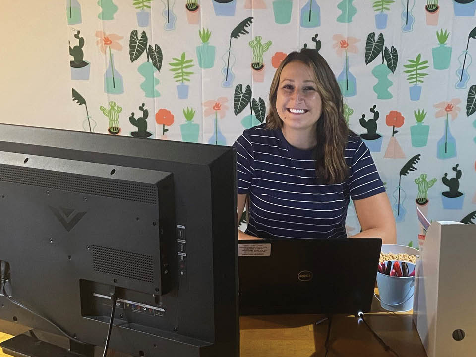 Teacher Gina Roselli sitting behind a computer, smiling