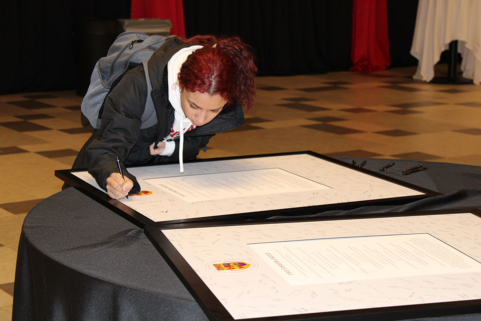 A member of the Class of 2026 signs the Fisher Creed.