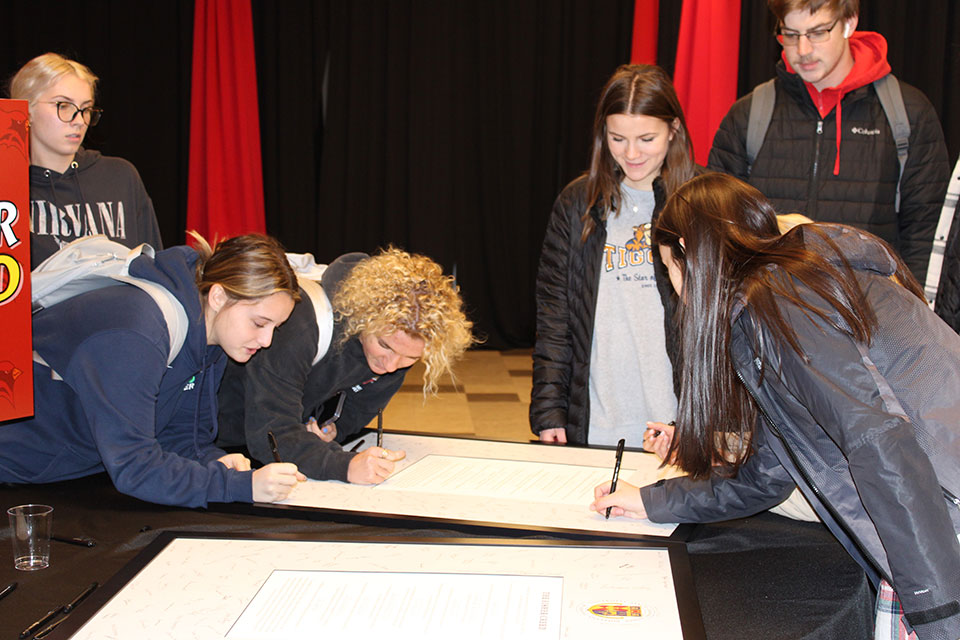 Students gather to sign framed copies of the Fisher Creed.