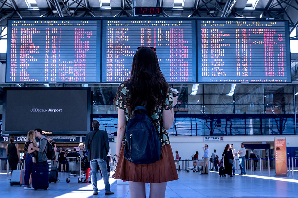 A woman looks at flight schedules at an airport.