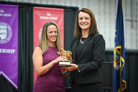 Ceremony keynote speaker, Dr. Julie Lenhard, accepts a mortar and pestle from Dean Christine Birnie.