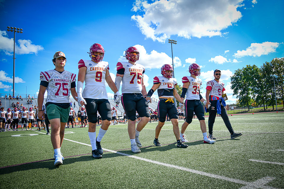 Fisher football players, along with their two honorary coaches, walk to the 50-yard line for the coin toss.