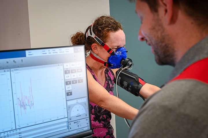 Dr. Wells tracks an athlete's stats while they ride a stationary bike.