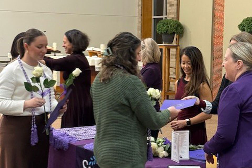 Students receive flowers and certificates during the honor society induction ceremony.