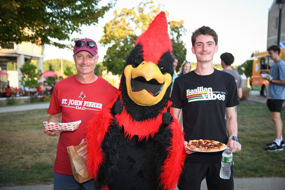 A Fisher dad and student pose with Beaks during Family Weekend.