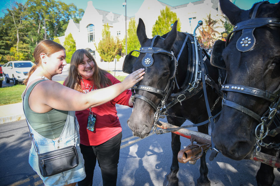 Two members of the Fisher community pet horses at the hayride station.