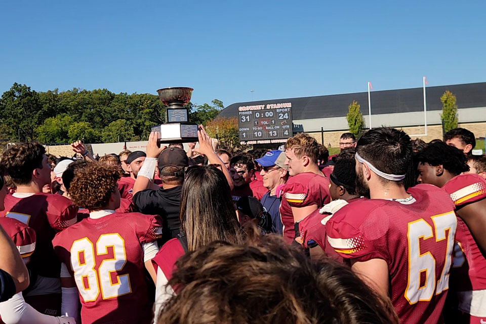 Members of the Fisher football team hold up the Teddi Trophy.