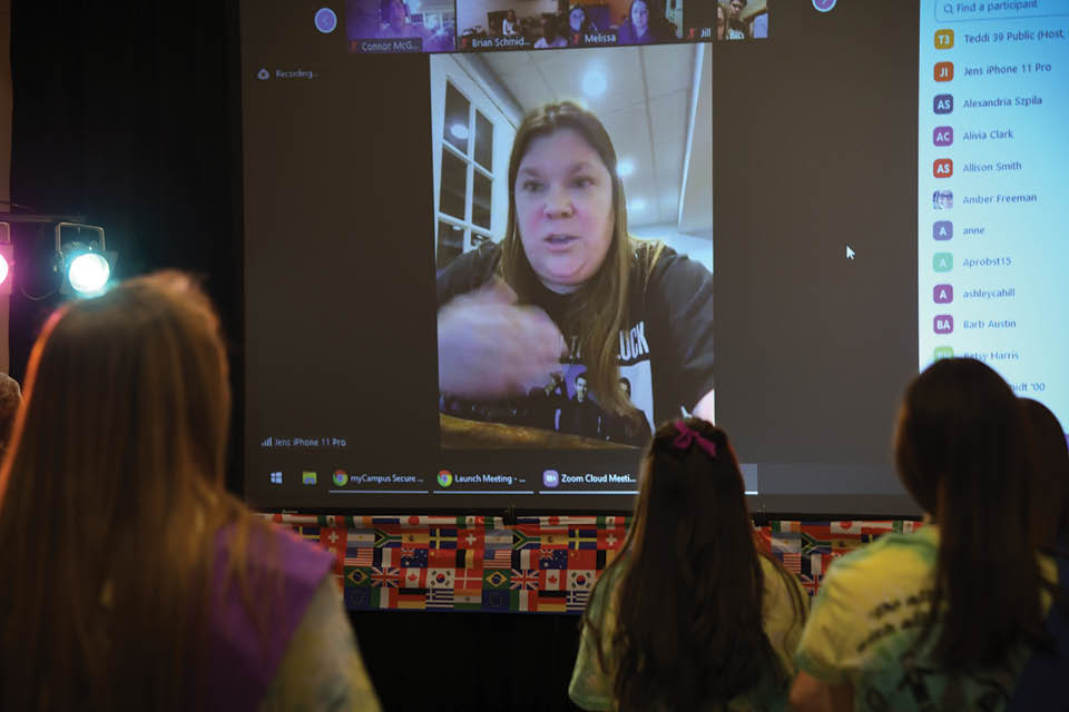 Jen Wolford speaks to Teddi dancers on a large screen via Zoom