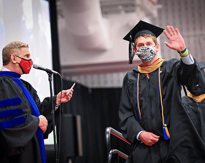 A new graduate of the School of Business waves to family in the audience.