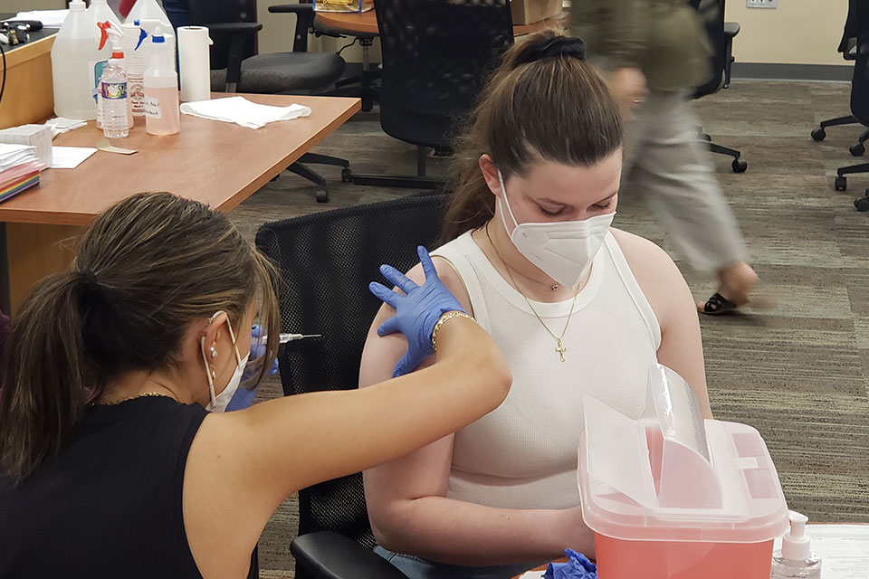 A student practices administering immunizations.