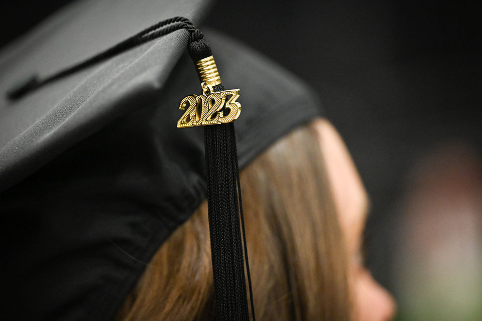 A Class of 2023 tassel hangs from a graduate's mortar board.