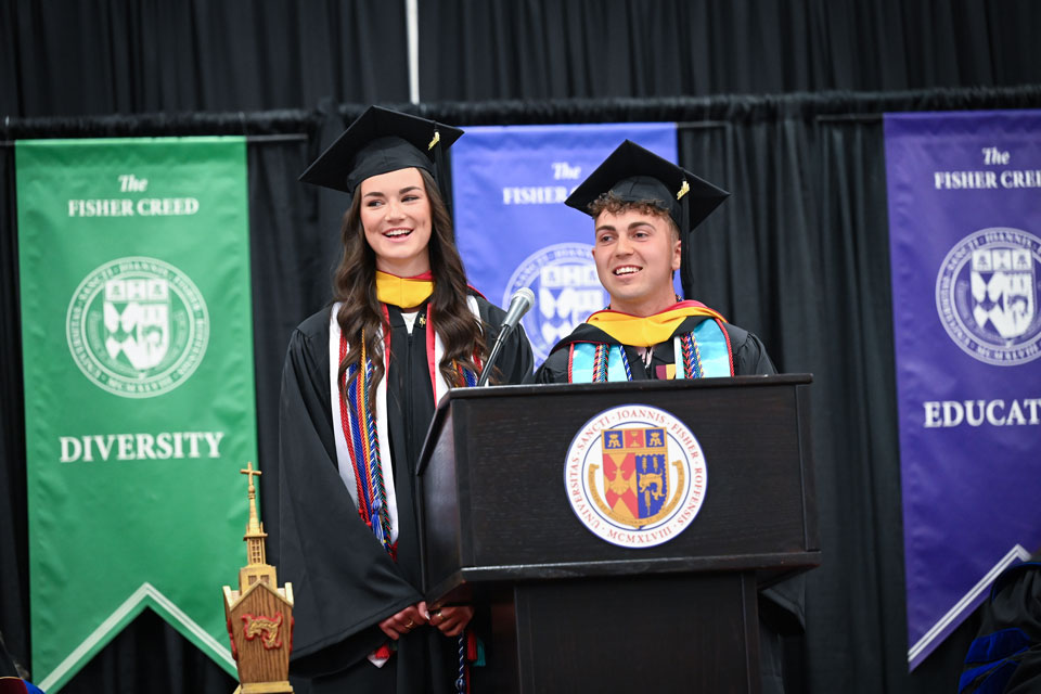 Two students speak at the 2024 School of Business Commencement ceremony.