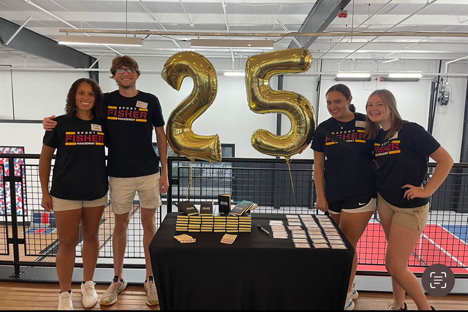 Members of the Sport Management Club host a booth celebrating the program's 25th anniversary.