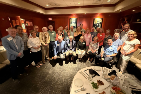 Alumni gathering for a group photo at a restaurant in Sarasota
