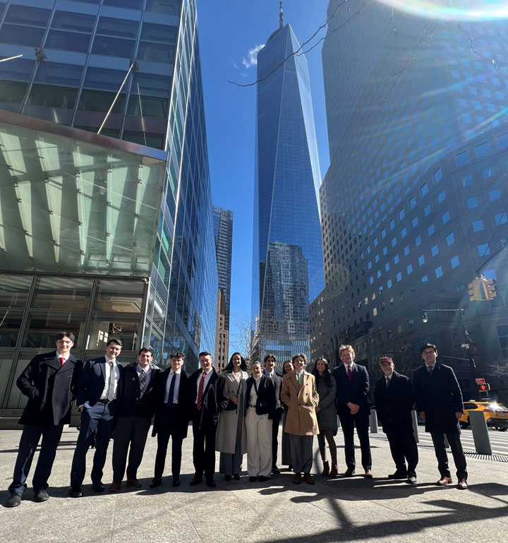 The Investment Club stands in front of skyscrapers in NYC.