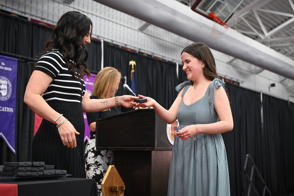 A nursing graduate receives a nursing pin.