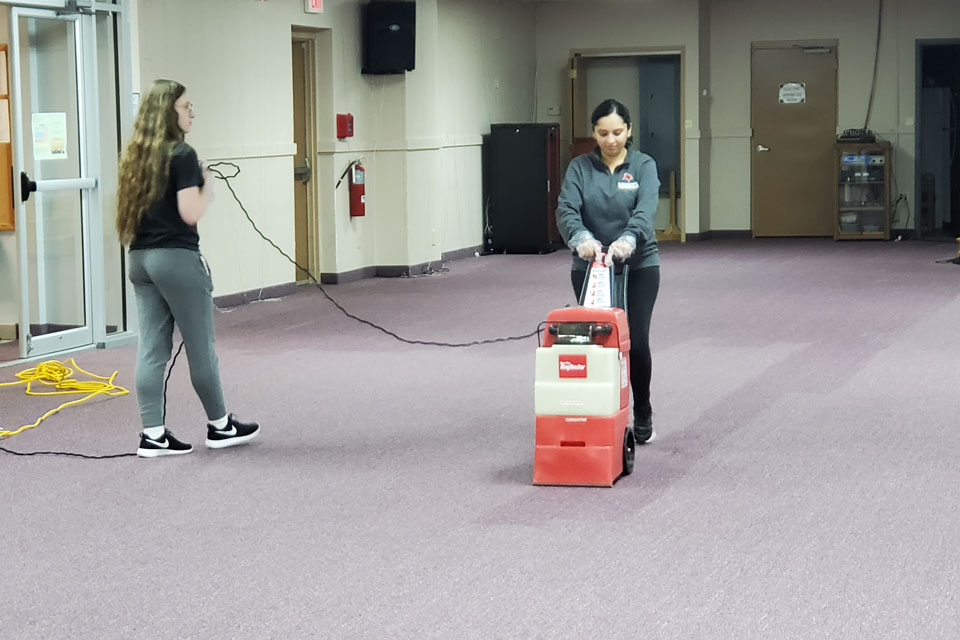 Two students clean the carpet at the Hindu Temple.