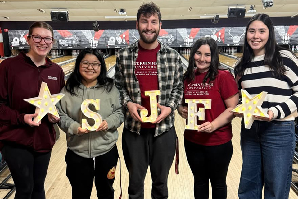 Andrew Beyler stands with fellow students holding SJF letters.