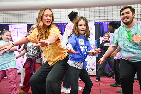 Students doing surfboard dancing on stage with a camper