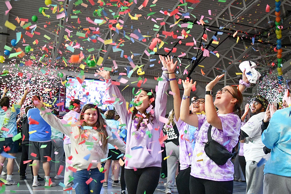 Students celebrating with arms in the air and confetti falling