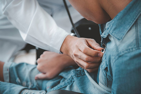 A healthcare provider uses a stethoscope to listen to a heart.