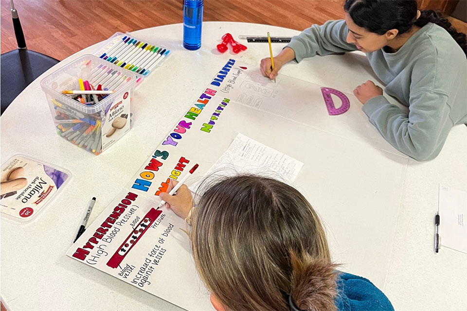 Students make educational posters for a community health fair at Blackfeed Reservation.