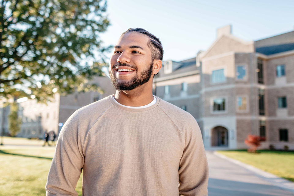 A Fisher student stands in front of the Upper Quad Residence Hall.
