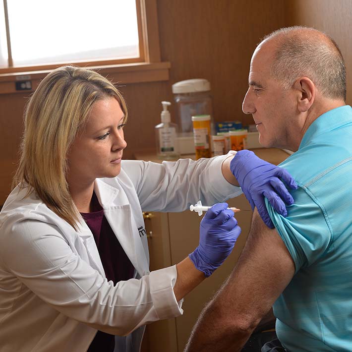 A student from the Wegmans School of Pharmacy administers a shot