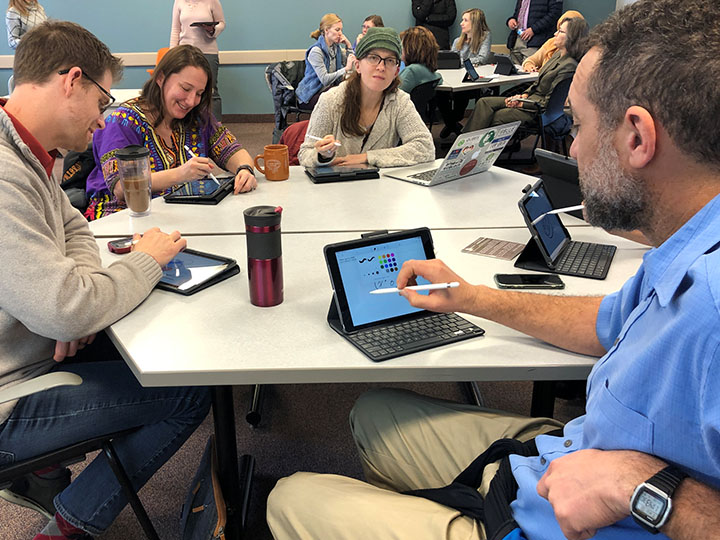 Faculty work in small groups using iPads.