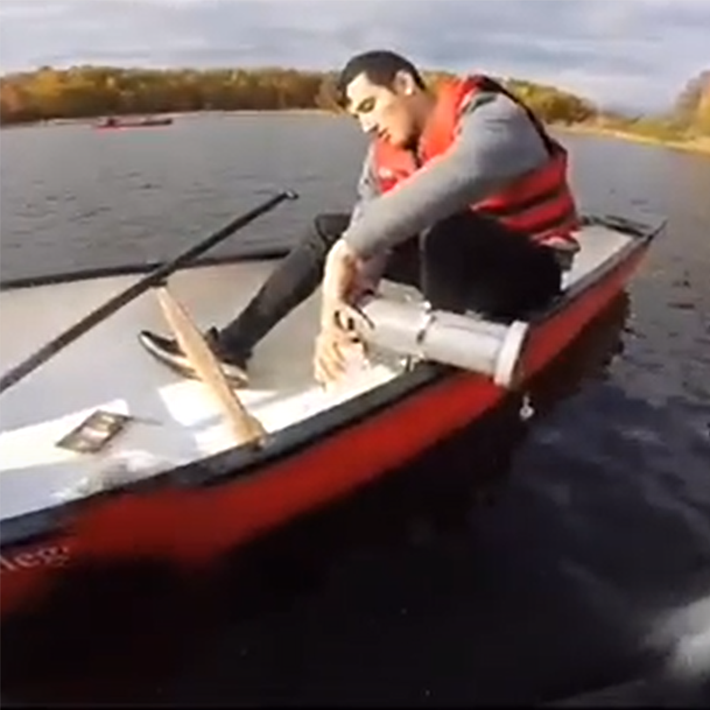 A student collecting a water sample in a boat.