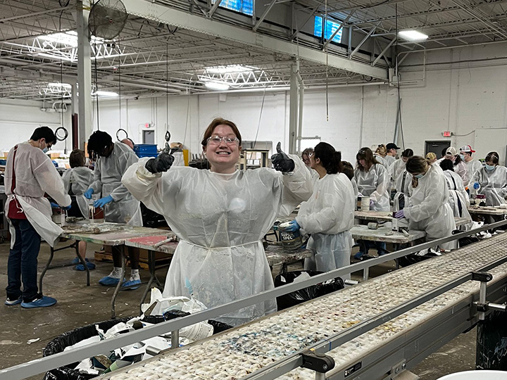 Students serving as part of a campus ministry trip with a student with two thumbs up in the center.