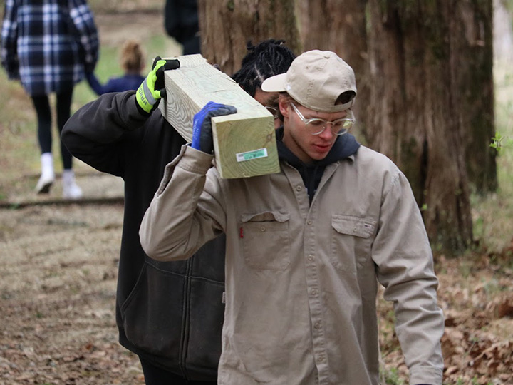 Students carry a beam during a community service project with campus ministry.