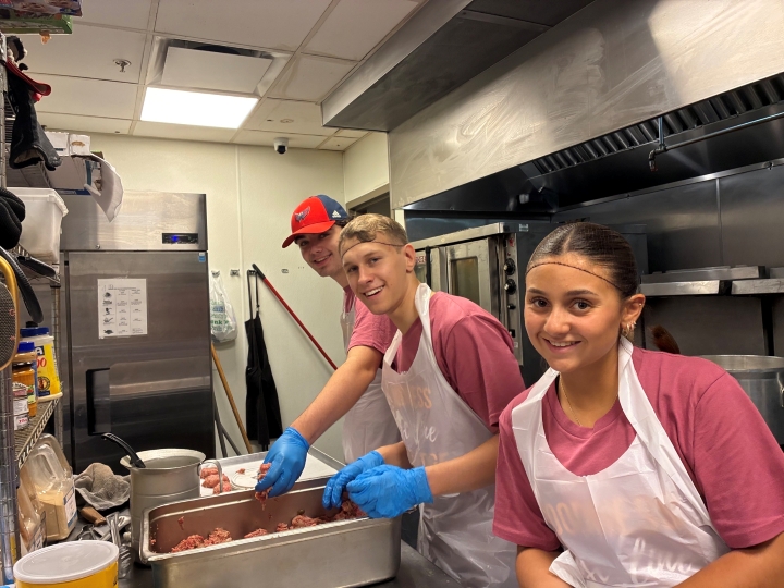 Students serving as part of a campus ministry trip helping in a commercial kitchen.